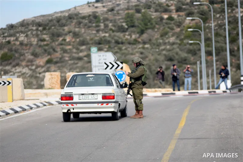 An Israeli soldier checks the documents of passengers of a Palestinian car on their way out of the West Bank village of Ein Sinya, northern Ramallah on February 1, 2016. Israel blocked non-residents from Ramallah after a...