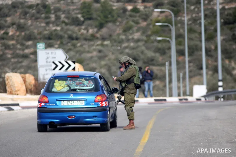 An Israeli soldier checks the documents of passengers of a Palestinian car on their way out of the West Bank village of Ein Sinya, northern Ramallah on February 1, 2016. Israel blocked non-residents from Ramallah after a...