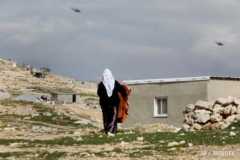 A Palestinian woman collects items from her home after it was demolished by Israeli bulldozers in a disputed military zone in the area of Musafir Jenbah, which includes several villages, south of the West Bank town of He...