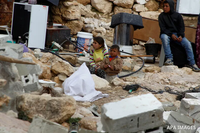Palestinian children sit next on the remains of their home after it was demolished by Israeli bulldozers in a disputed military zone in the area of Musafir Jenbah, which includes several villages, south of the West Bank...