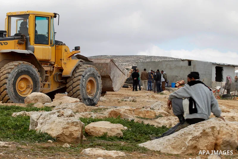 A Palestinian man sit during Israeli bulldozers demolish Palestinian homes in a disputed military zone in the area of Musafir Jenbah, which includes several villages, south of the West Bank town of Hebron on February 2,...