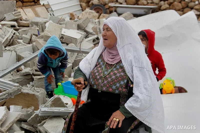 A Palestinian woman sits next on the remains of her home after it was demolished by Israeli bulldozers in a disputed military zone in the area of Musafir Jenbah, which includes several villages, south of the West Bank to...