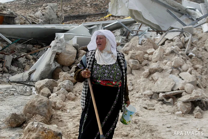 A Palestinian woman stands next on the remains of her home after it was demolished by Israeli bulldozers in a disputed military zone in the area of Musafir Jenbah, which includes several villages, south of the West Bank...