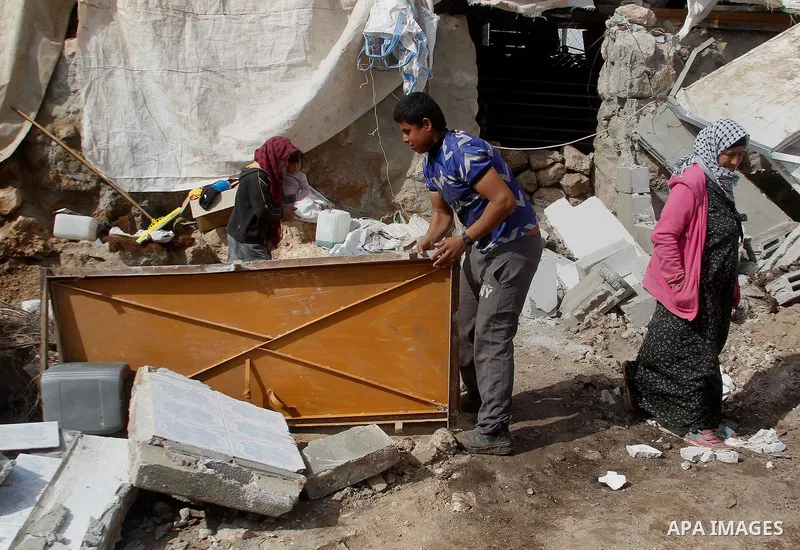 Palestinians collect items from their home after it was demolished by Israeli bulldozers in a disputed military zone in the area of Musafir Jenbah, which includes several villages, south of the West Bank town of Hebron o...