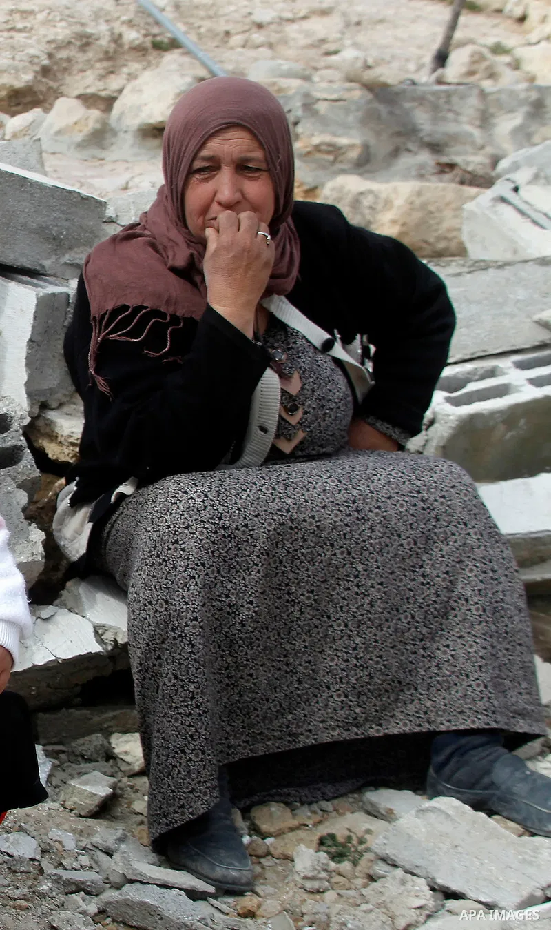 A Palestinian woman sits next on the remains of her home after it was demolished by Israeli bulldozers in a disputed military zone in the area of Musafir Jenbah, which includes several villages, south of the West Bank to...
