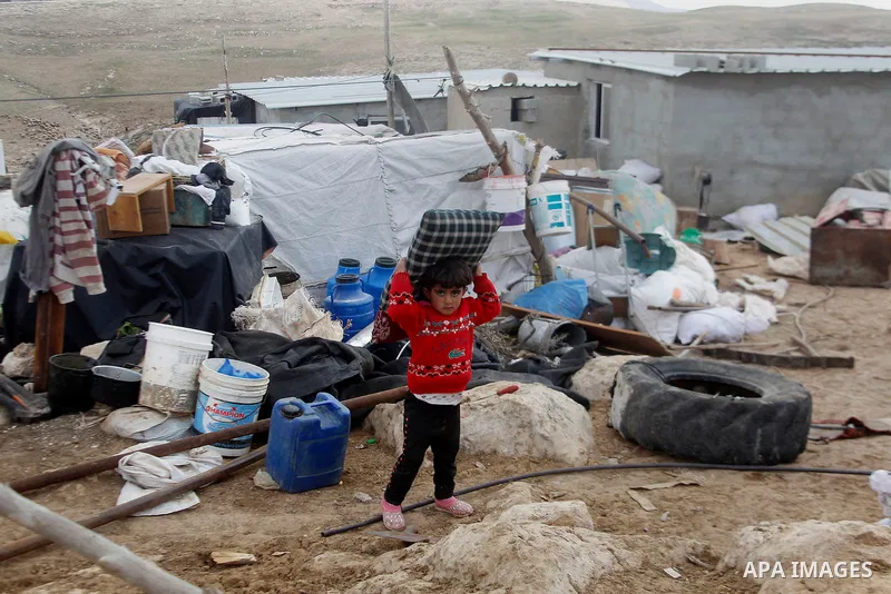 A Palestinian child collects items from his family's home after it was demolished by Israeli bulldozers in a disputed military zone in the area of Musafir Jenbah, which includes several villages, south of the West Bank t...