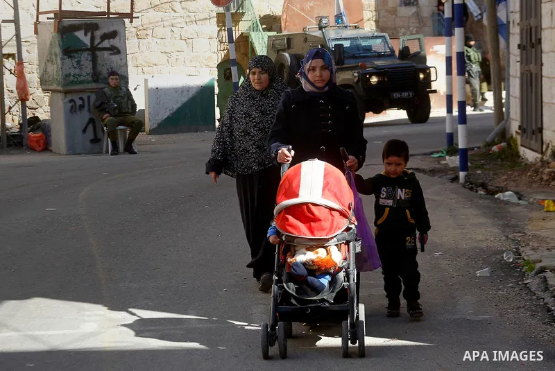 Palestinians walk in front of houses which Israeli settlers try to take over, in the West Bank city of Hebron, 03 February 2016. The building is near the religious site known to Jews as the Cave of the Patriarchs and to...