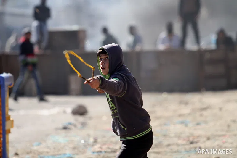 A Palestinian protester uses a slingshot to throw stones toward Israeli security forces during clashes in Qabatiya, a town near Jenin in the north of the Israeli-occupied West Bank, on February 4, 2016. Israeli forces lo...
