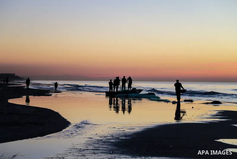 Palestinian fishermen work during the sunset on the beach of Gaza city on Feb. 04, 2016. Photo by Mohammed Dahman
