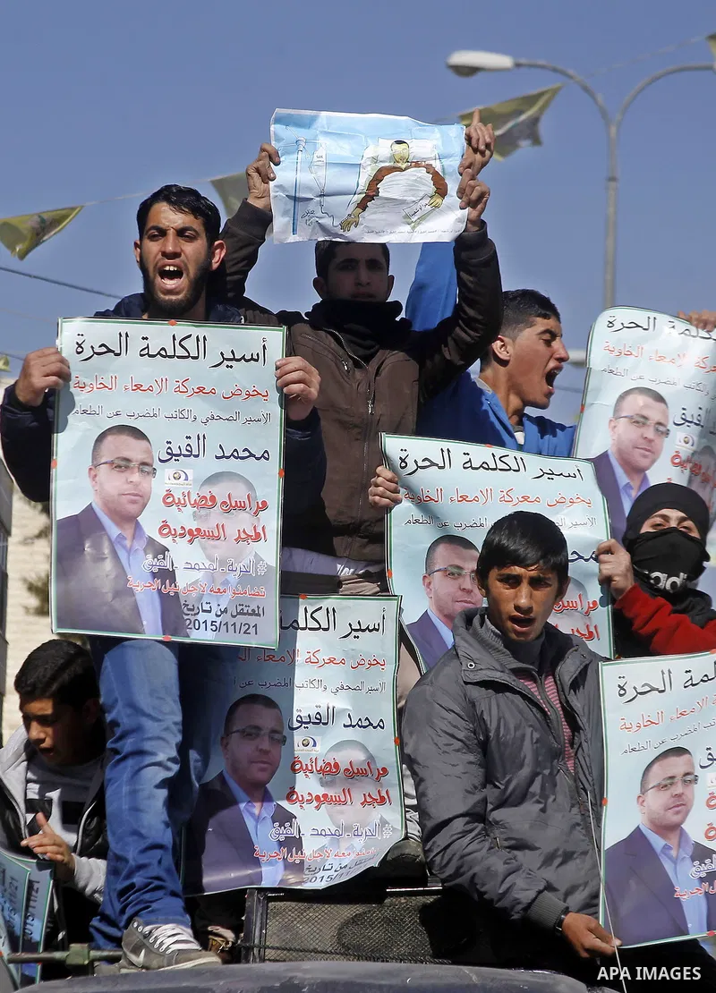 Palestinian demonstrators hold posters bearing portraits of Palestinian journalist Mohammed al-Qiq who is imprisoned in an Israeli jail during a protest in support of his hunger strike in the West Bank city of Hebron on...
