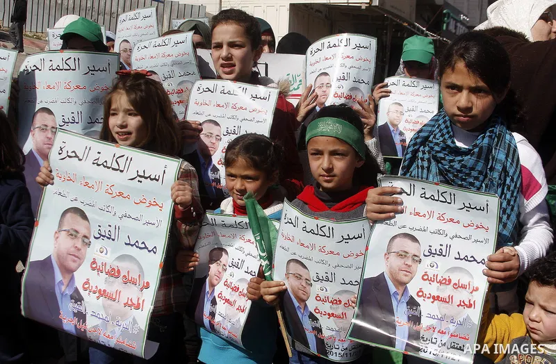 Palestinian demonstrators hold posters bearing portraits of Palestinian journalist Mohammed al-Qiq who is imprisoned in an Israeli jail during a protest in support of his hunger strike in the West Bank city of Hebron on...