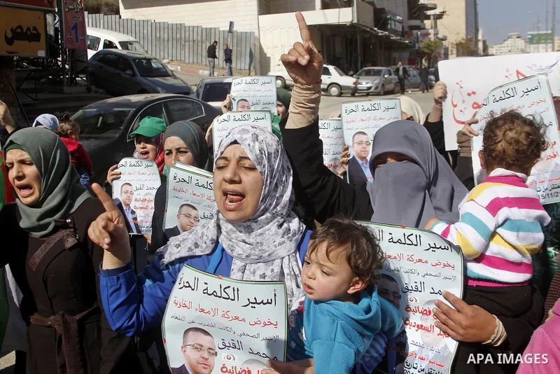 Palestinian demonstrators hold posters bearing portraits of Palestinian journalist Mohammed al-Qiq who is imprisoned in an Israeli jail during a protest in support of his hunger strike in the West Bank city of Hebron on...