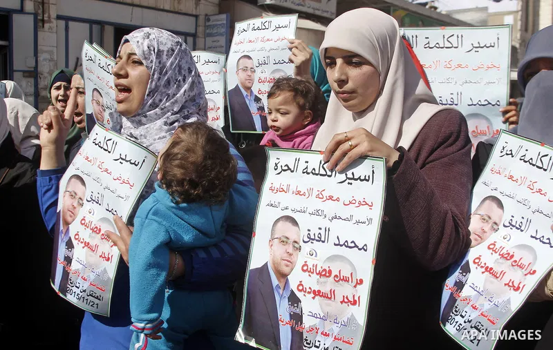 The wife of Palestinian imprisoned journalist Mohammed al-Qiq, Fayha Shalash holds a poster bearing portrait of her husband's who is imprisoned in an Israeli jail during a protest in support of his hunger strike in the W...