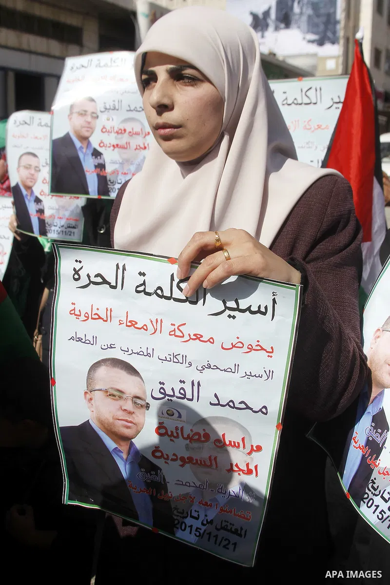 The wife of Palestinian imprisoned journalist Mohammed al-Qiq, Fayha Shalash holds a poster bearing portrait of her husband's who is imprisoned in an Israeli jail during a protest in support of his hunger strike in the W...