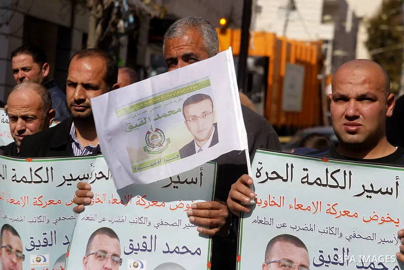 Palestinian demonstrators hold posters bearing portraits of Palestinian journalist Mohammed al-Qiq who is imprisoned in an Israeli jail during a protest in support of his hunger strike in the West Bank city of Hebron on...