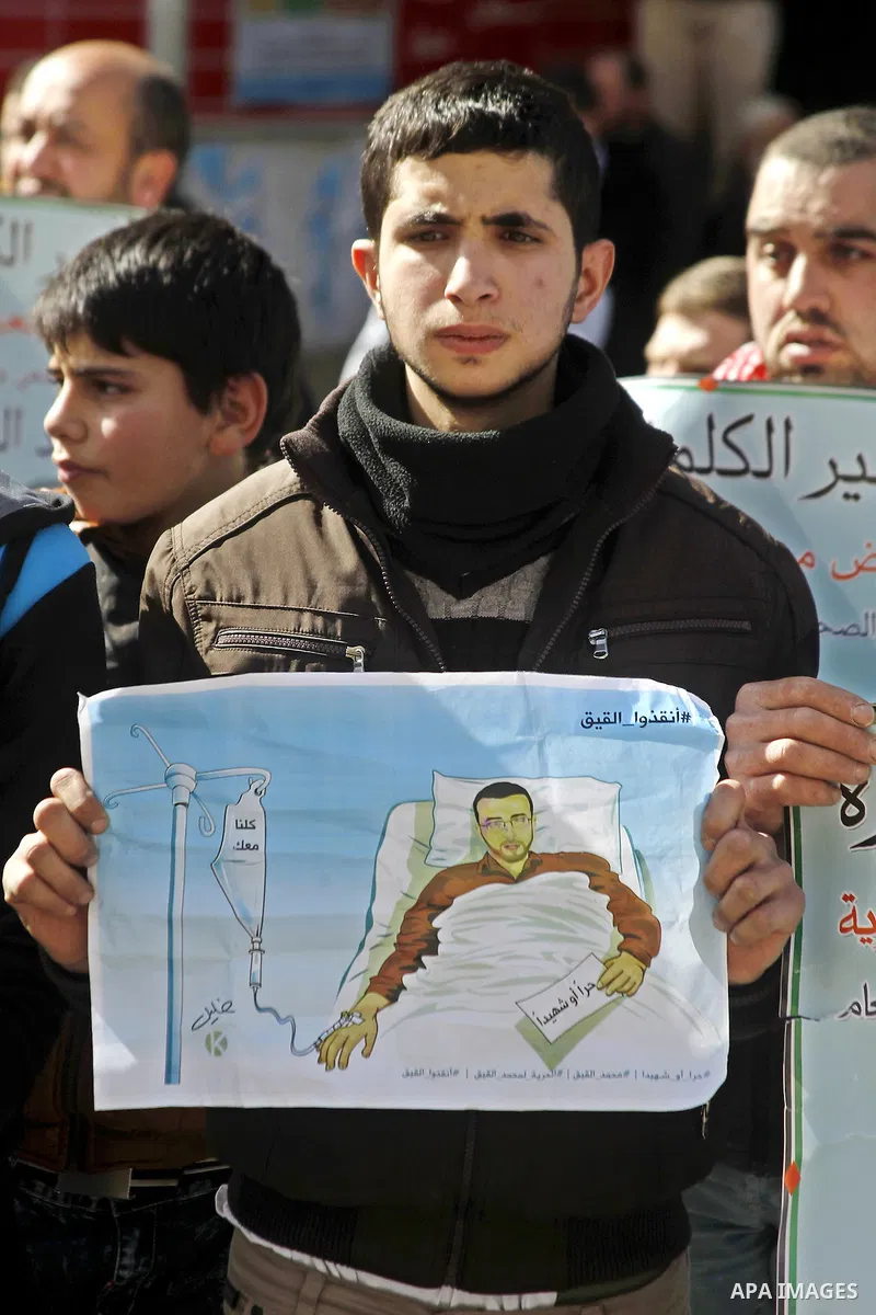 Palestinian demonstrators hold posters bearing portraits of Palestinian journalist Mohammed al-Qiq who is imprisoned in an Israeli jail during a protest in support of his hunger strike in the West Bank city of Hebron on...