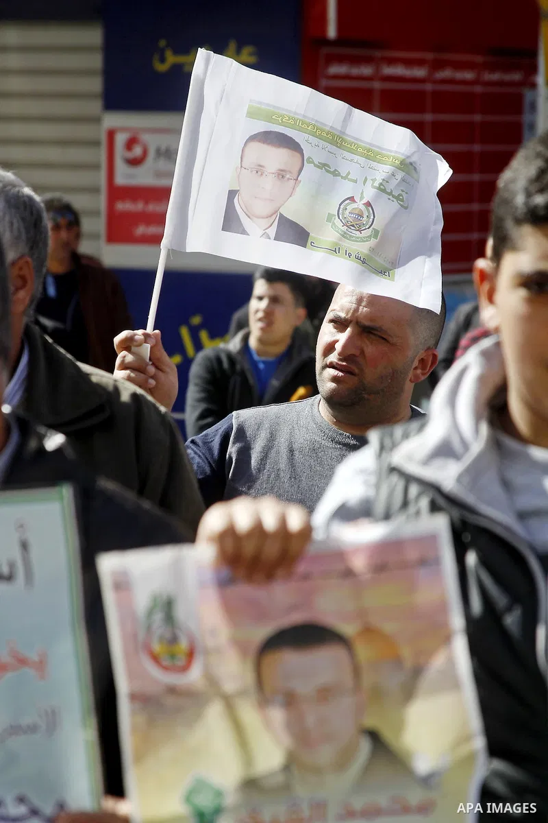 Palestinian demonstrators hold posters bearing portraits of Palestinian journalist Mohammed al-Qiq who is imprisoned in an Israeli jail during a protest in support of his hunger strike in the West Bank city of Hebron on...