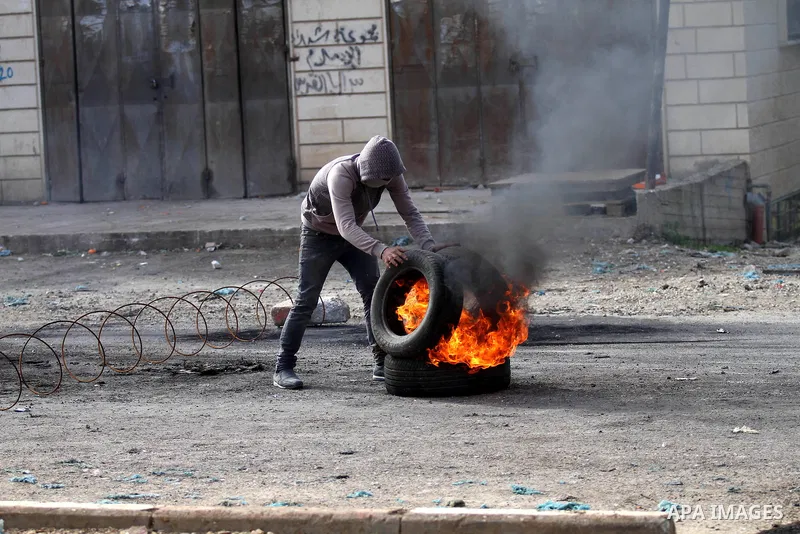A Palestinian protester burns tires during clashes with Israeli security forces in the Palestinian town of Qabatiya, near Jenin in the north of the Israeli-occupied West Bank, on February 5, 2016. The Israeli army blocke...