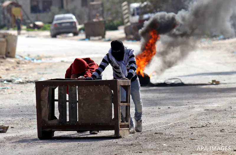 Palestinian protesters push a container during clashes with Israeli security forces in the Palestinian town of Qabatiya, near Jenin in the north of the Israeli-occupied West Bank, on February 5, 2016. The Israeli army bl...