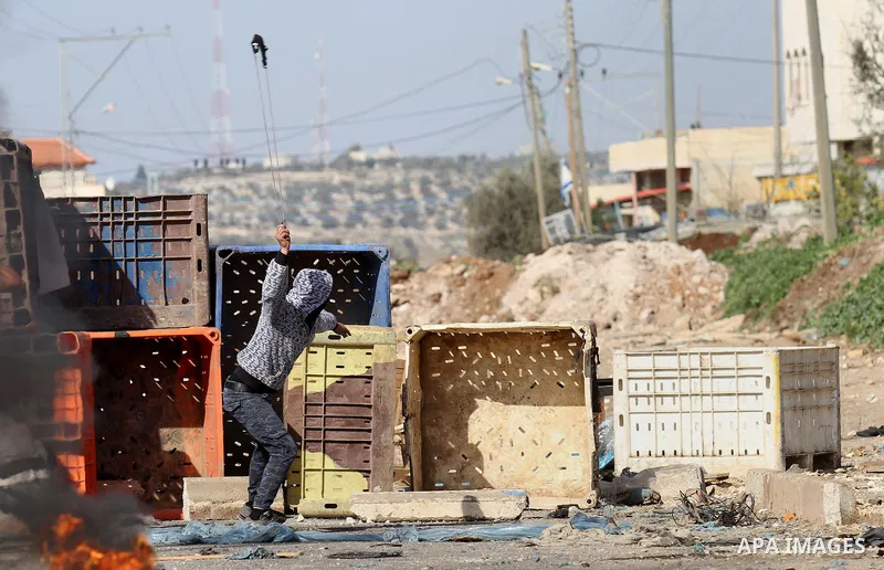 A Palestinian protester throws stones towards Israeli security forces during clashes in the Palestinian town of Qabatiya, near Jenin in the north of the Israeli-occupied West Bank, on February 5, 2016. The Israeli army b...