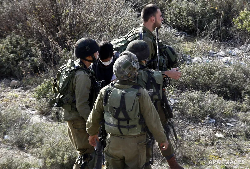 Israeli security forces detain a Palestinian man as their colleagues give back the body of Haitham al-Bau, who was shot dead by Israeli soldiers after throwing a petrol bomb at a military jeep, to members of the Palestin...