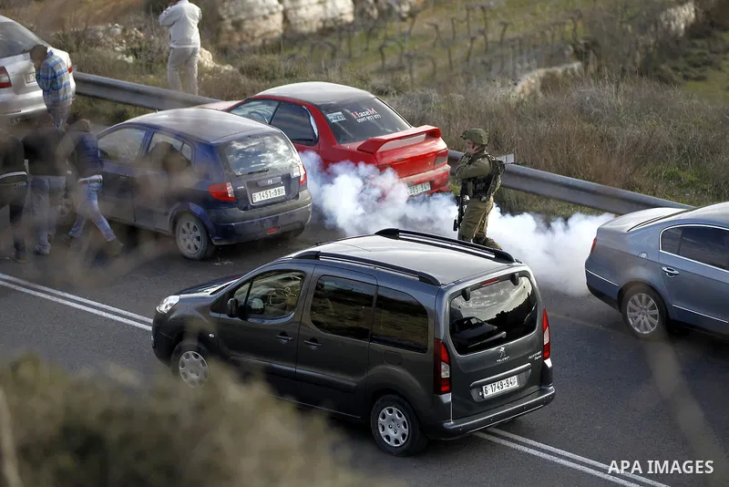 A member of Israeli security forces stand guard as their colleagues give back the body of Haitham al-Bau, who was shot dead by Israeli soldiers after throwing a petrol bomb at a military jeep, to members of the Palestini...