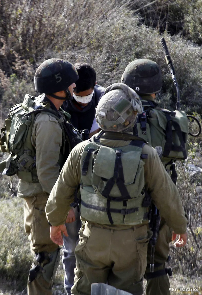 Israeli security forces detain a Palestinian man as their colleagues give back the body of Haitham al-Bau, who was shot dead by Israeli soldiers after throwing a petrol bomb at a military jeep, to members of the Palestin...