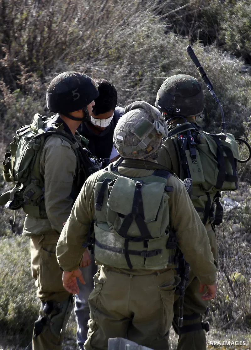 Israeli security forces detain a Palestinian man as their colleagues give back the body of Haitham al-Bau, who was shot dead by Israeli soldiers after throwing a petrol bomb at a military jeep, to members of the Palestin...