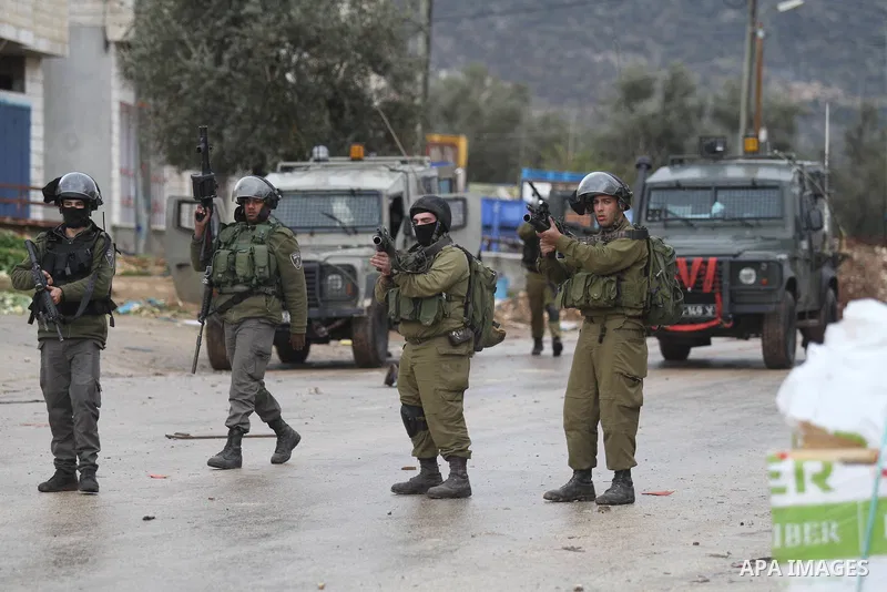 Israeli soldiers walk near a burning tyre during clashes with Palestinians in the West Bank town of Qabatya, near Jenin February 6, 2016. On Wednesday, three young Palestinian men from Qabatya wielding guns, knives and p...