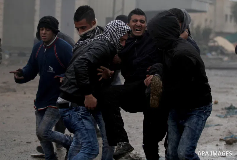 A Palestinian demonstrator runs to help his injured comrade during clashes with Israeli security forces in the village of Qabatiya, near the West Bank town of Jenin, during clashes on February 6, 2016. Three Palestinians...