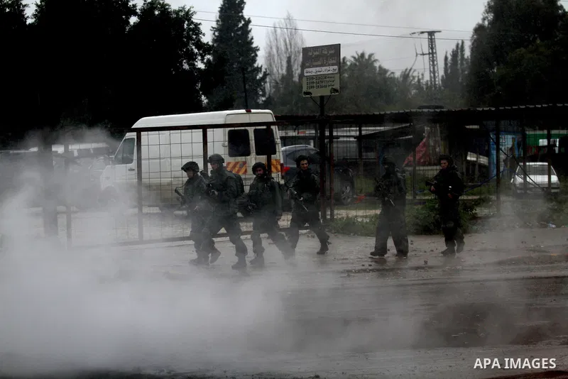 Israeli soldiers walk near a burning tyre during clashes with Palestinians in the West Bank town of Qabatya, near Jenin February 6, 2016. On Wednesday, three young Palestinian men from Qabatya wielding guns, knives and p...
