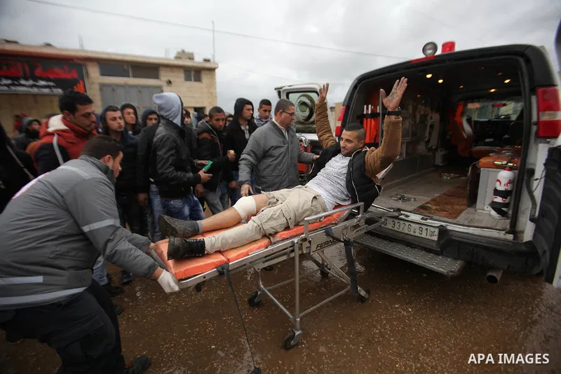 A Palestinian demonstrator runs to help his injured comrade during clashes with Israeli security forces in the village of Qabatiya, near the West Bank town of Jenin, during clashes on February 6, 2016. Three Palestinians...
