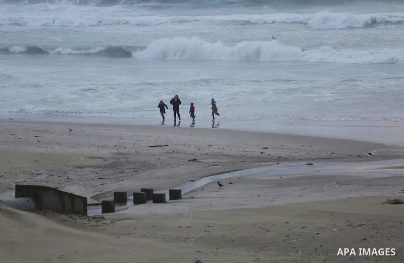 Palestinians walk on the beach of Gaza city following a heavy rain, on Feb. 07, 2016. Photo by Mohammed Asad