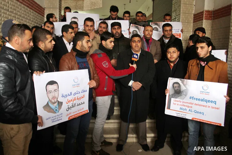 Palestinian journalists hold posters bearing portraits of Palestinian journalist Mohammed al-Qiq who is imprisoned in an Israeli jail during a protest in support of his hunger strike in Rafah in the southern Gaza strip o...