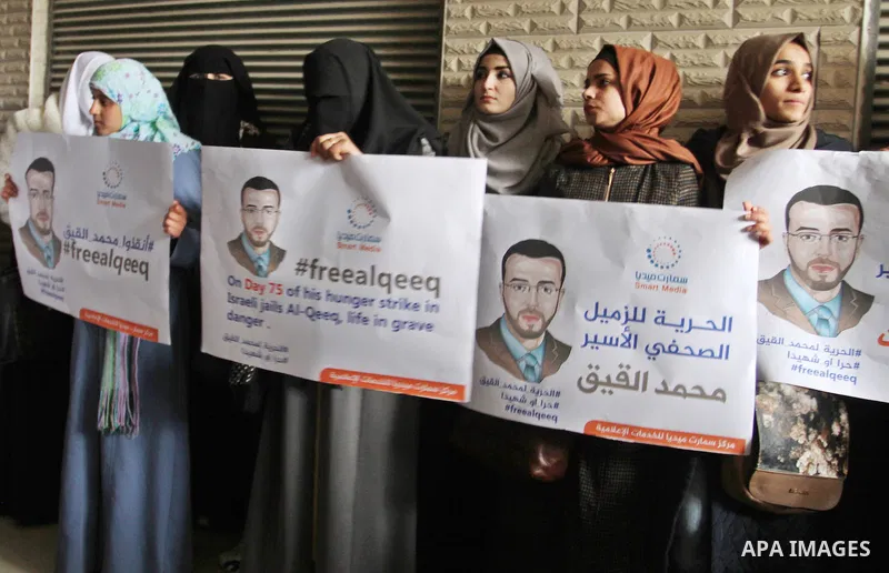 Palestinian journalists hold posters bearing portraits of Palestinian journalist Mohammed al-Qiq who is imprisoned in an Israeli jail during a protest in support of his hunger strike in Rafah in the southern Gaza strip o...