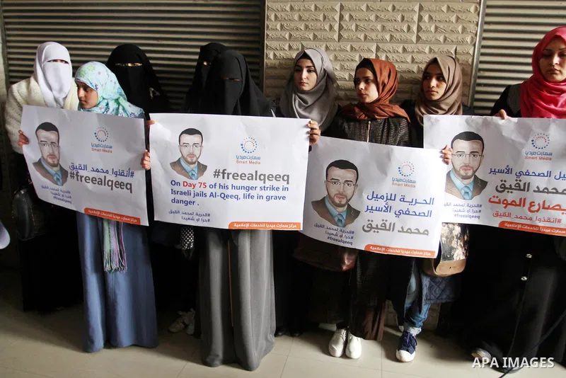 Palestinian journalists hold posters bearing portraits of Palestinian journalist Mohammed al-Qiq who is imprisoned in an Israeli jail during a protest in support of his hunger strike in Rafah in the southern Gaza strip o...