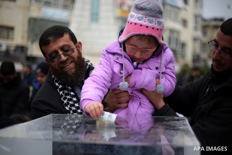 Palestinian Islamic Jihad leader Khader Adnan holds his girl as she donates money during a fundraising campaign aimed at rebuilding the families houses of Jerusalem Martyrs, after demolished by Israeli authorities in the...