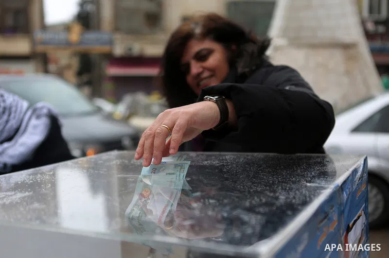 A Palestinian woman donates money during a fundraising campaign aimed at rebuilding the families houses of Jerusalem Martyrs, after demolished by Israeli authorities in the West Bank city of Ramallah, on February 8, 2016...
