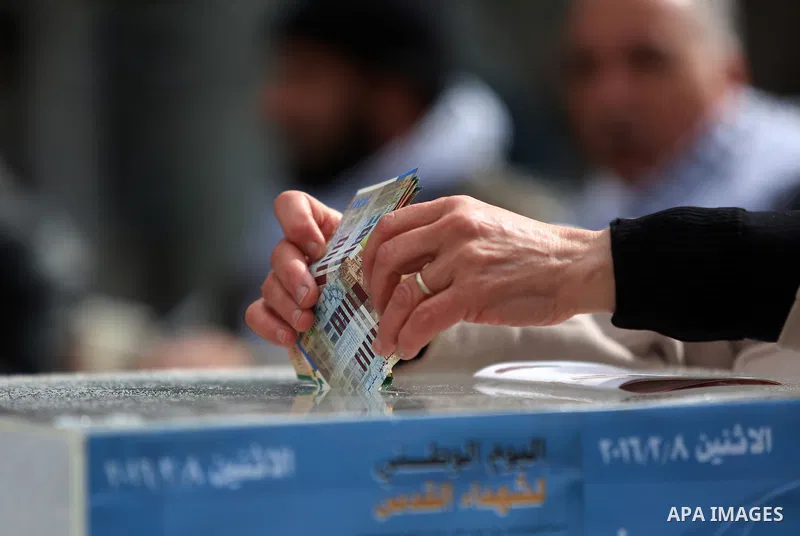 A Palestinian man donates money during a fundraising campaign aimed at rebuilding the families houses of Jerusalem Martyrs, after demolished by Israeli authorities in the West Bank city of Ramallah, on February 8, 2016....