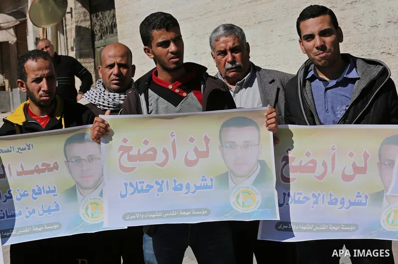 Palestinians hold posters during a demonstration in support of hunger striking Palestinian journalist Mohammed al-Qiq, in front of Red cross office in Gaza city on February 9, 2016. The 33-year-old television reporter wi...
