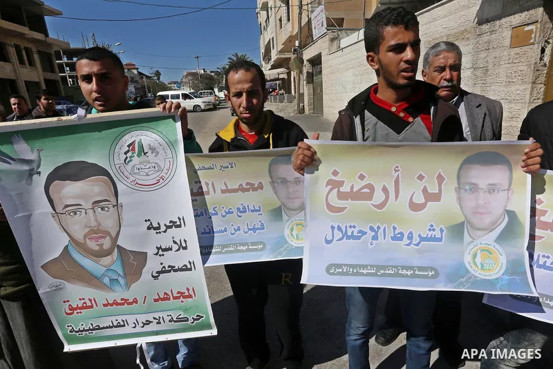 Palestinians hold posters during a demonstration in support of hunger striking Palestinian journalist Mohammed al-Qiq, in front of Red cross office in Gaza city on February 9, 2016. The 33-year-old television reporter wi...