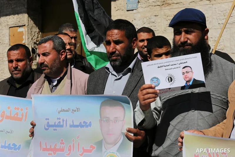 Palestinians hold posters during a demonstration in support of hunger striking Palestinian journalist Mohammed al-Qiq, in front of Red cross office in Gaza city on February 9, 2016. The 33-year-old television reporter wi...