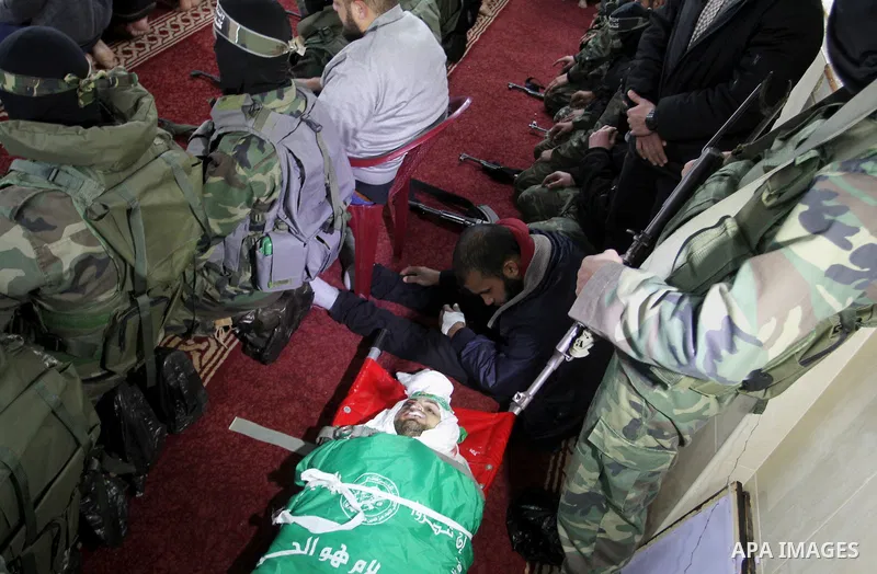 Palestinian members of the Ezzedine al-Qassam Brigades, the armed wing of the Hamas movement pray over the body of their comrade Marwan Maarouf, 27, during his funeral in Khan Yunis in the southern Gaza Strip, on Februar...