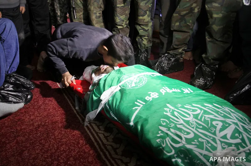 Palestinian members of the Ezzedine al-Qassam Brigades, the armed wing of the Hamas movement pray over the body of their comrade Marwan Maarouf, 27, during his funeral in Khan Yunis in the southern Gaza Strip, on Februar...