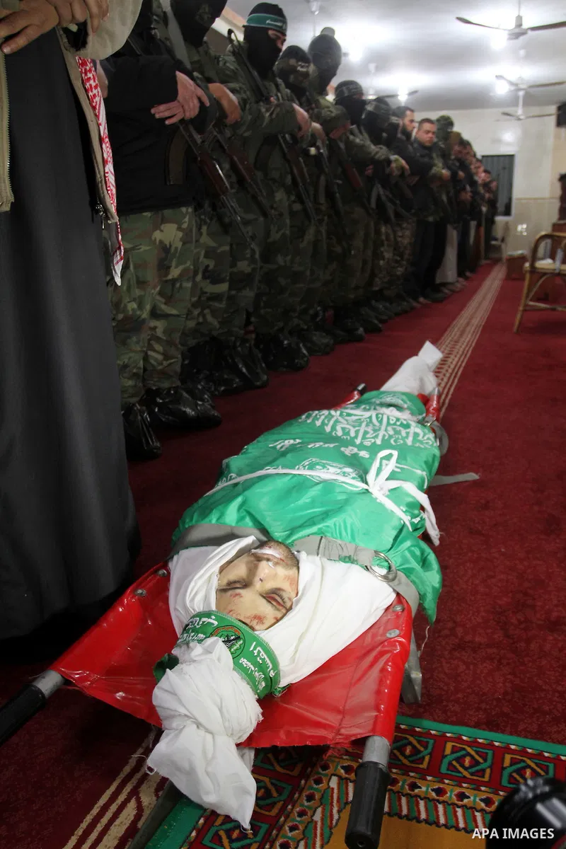 Palestinian members of the Ezzedine al-Qassam Brigades, the armed wing of the Hamas movement pray over the body of their comrade Marwan Maarouf, 27, during his funeral in Khan Yunis in the southern Gaza Strip, on Februar...