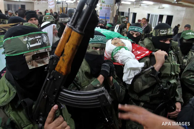 Palestinian members of the Ezzedine al-Qassam Brigades, the armed wing of the Hamas movement carry the body of their comrade Marwan Maarouf, 27, during his funeral in Khan Yunis in the southern Gaza Strip, on February 9,...