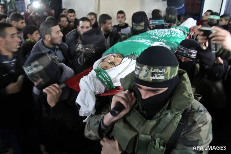 Palestinian members of the Ezzedine al-Qassam Brigades, the armed wing of the Hamas movement carry the body of their comrade Marwan Maarouf, 27, during his funeral in Khan Yunis in the southern Gaza Strip, on February 9,...