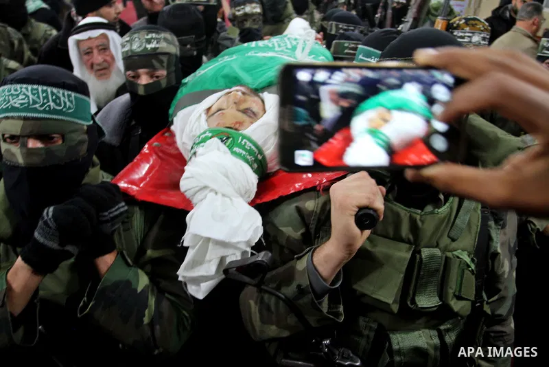 Palestinian members of the Ezzedine al-Qassam Brigades, the armed wing of the Hamas movement carry the body of their comrade Marwan Maarouf, 27, during his funeral in Khan Yunis in the southern Gaza Strip, on February 9,...