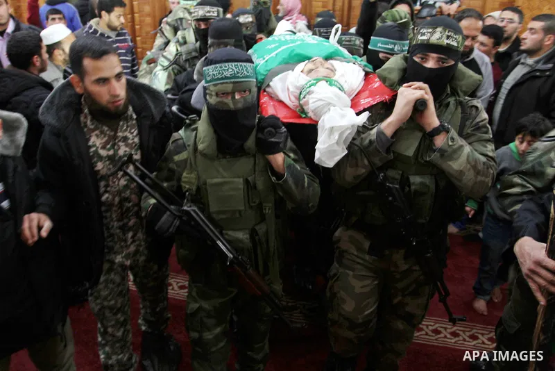 Palestinian members of the Ezzedine al-Qassam Brigades, the armed wing of the Hamas movement carry the body of their comrade Marwan Maarouf, 27, during his funeral in Khan Yunis in the southern Gaza Strip, on February 9,...