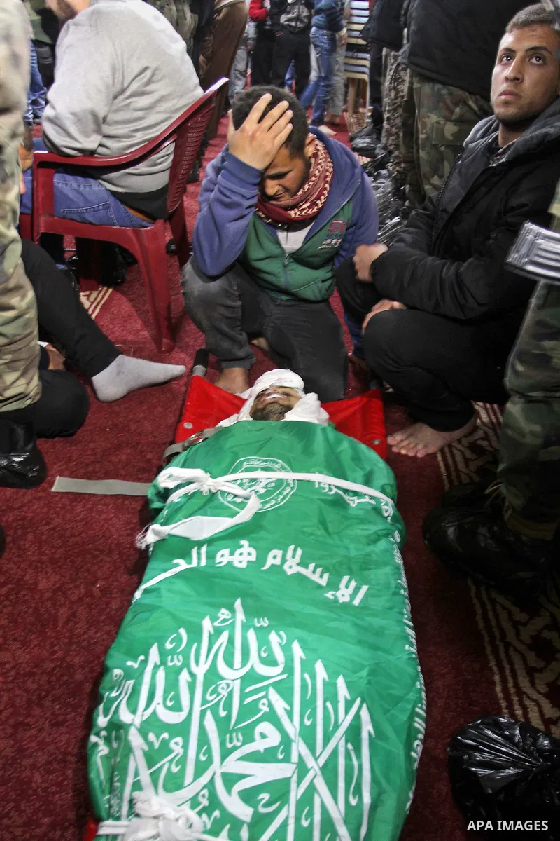 Palestinian members of the Ezzedine al-Qassam Brigades, the armed wing of the Hamas movement pray over the body of their comrade Marwan Maarouf, 27, during his funeral in Khan Yunis in the southern Gaza Strip, on Februar...